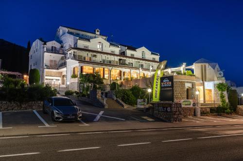 un coche aparcado en un aparcamiento frente a un edificio en Hotel Vicko en Starigrad-Paklenica