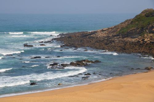 a beach with rocks in the water and the ocean at Well Hotel & Spa in Maceira