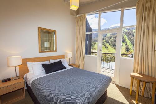 a bedroom with a bed and a large window at The Denman Hotel in Thredbo in Thredbo