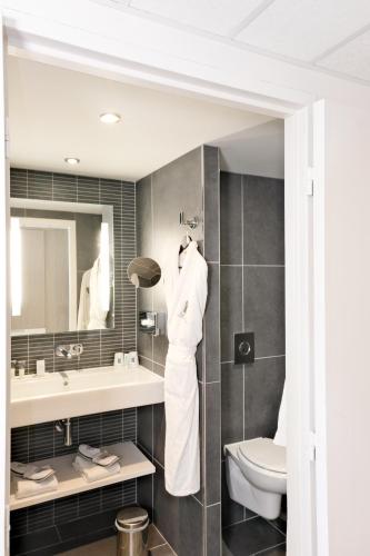 a bathroom with a sink and a toilet and a mirror at Thalazur Cabourg - Hôtel & Spa in Cabourg