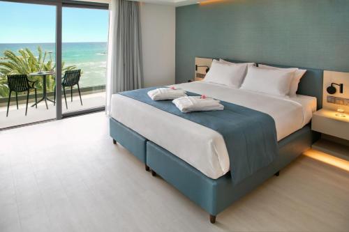 a bedroom with a bed with a view of the ocean at Mercure Larnaca Beach Resort in Larnaka