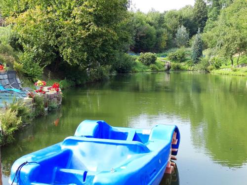 un barco azul en un río con árboles en el fondo en Roomy Apartment in Lichtenhain with Pond, en Lichtenhain