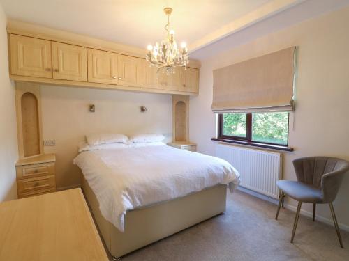 a bedroom with a bed and a chair and a chandelier at 27 Brocklehurst in Oakham