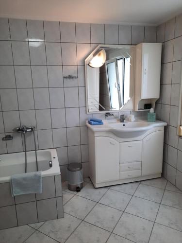 uma casa de banho com um lavatório, uma banheira e um espelho. em Vasilis Garden House em Kavala