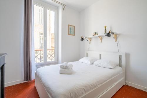 une chambre avec un lit avec des draps blancs et une fenêtre dans l'établissement Elana - Bel appartement dans la quartier du Camas, à Marseille
