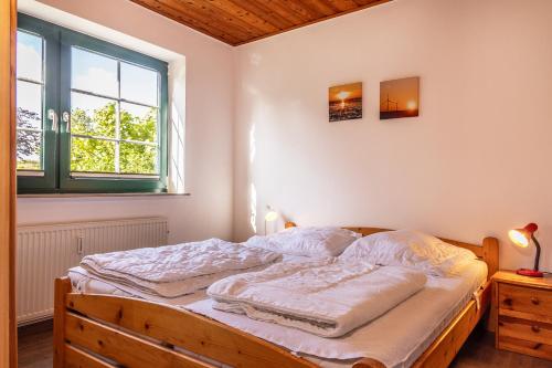Schlafzimmer mit einem Bett mit einem Holzrahmen und einem Fenster in der Unterkunft 50042... in Carolinensiel