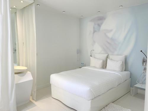 a white bedroom with a white bed and a mirror at Blc Design Hotel in Paris