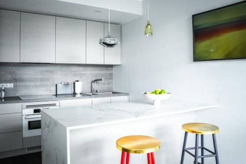 a kitchen with white cabinets and gold stools at 8ERA Business Executive Rotermanni Apartments in Tallinn
