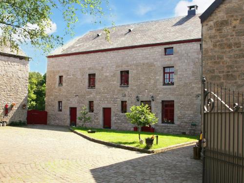un antiguo edificio de piedra con puertas rojas y una valla en Luxury Holiday Home in Melreux Hotton with Sauna en Melreux