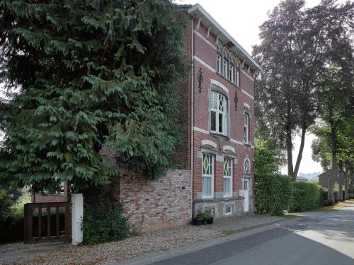 um edifício de tijolos com uma árvore ao lado de uma rua em Suave Holiday Home in Stavelot with Infrared Sauna em Stavelot