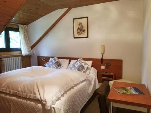 a bedroom with a white bed and a table at Hôtel L'Amoulat in Gourette