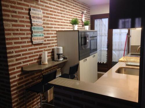 a kitchen with a counter with chairs and a microwave at La plazuela Navaluenga in Navaluenga