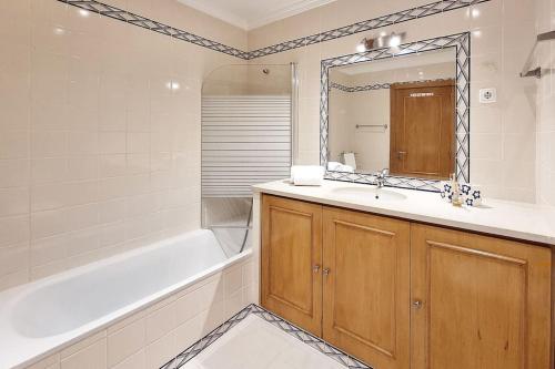 uma casa de banho com um lavatório, uma banheira e um espelho. em Sea Beside em Albufeira