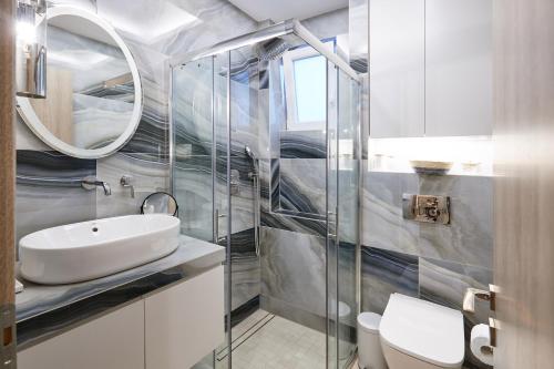 a bathroom with a sink and a toilet and a mirror at Horizon Seaside Living in Iraklitsa