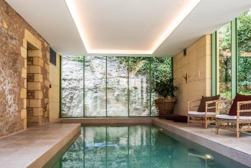 una piscina en medio de una casa con paredes de cristal en Hôtel Restaurant de Bouilhac, Spa & Wellness - Les Collectionneurs, en Montignac