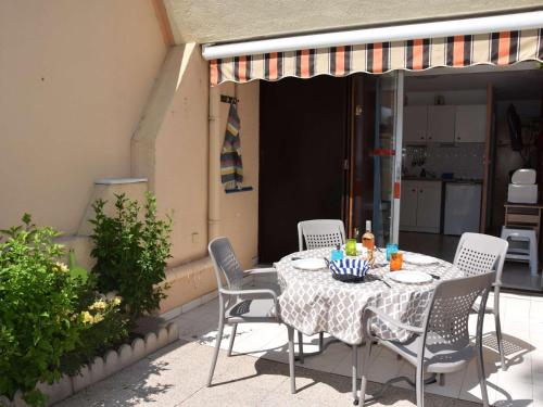 une table et des chaises assises sur une terrasse dans l'établissement Studio cabine avec piscine, plage directe, terrasse et parking - Animaux acceptés - FR-1-387-53, à Marseillan