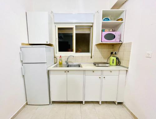 uma cozinha branca com um lavatório e um frigorífico em КВАРТИРА У МОРЯ! em Haifa