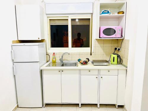 uma cozinha com armários brancos, um lavatório e um micro-ondas em КВАРТИРА У МОРЯ! em Haifa