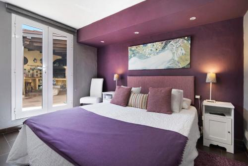 a purple bedroom with a large bed and a window at Los Veroles in Agaete