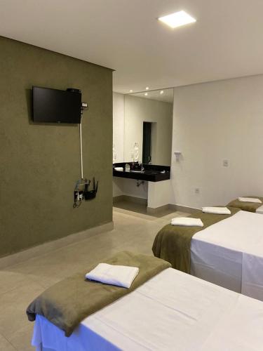 a hotel room with two beds and a tv on the wall at CHALÉS VALE DO LAGO in Capitólio