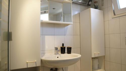 a white bathroom with a sink and a mirror at Wad'N Huis in Westerland