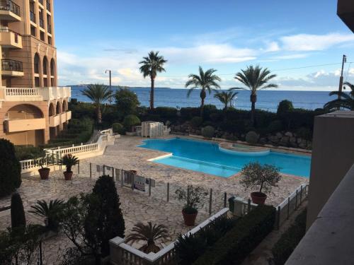une vue sur une piscine avec des palmiers et l'océan dans l'établissement Appartement 531, à Cannes