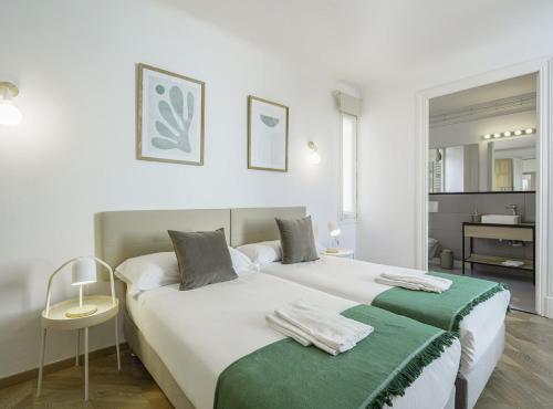 2 Betten in einem weißen Zimmer mit grüner Bettwäsche in der Unterkunft SibsBcn-Paseo de Gracia Penthouse-Luxury-Terraces in Barcelona