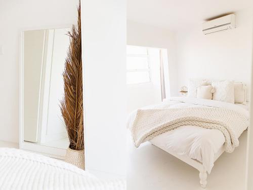 a white bedroom with a bed and a mirror at Boho Beach Retreat in La Lucia, Umhlanga in Durban
