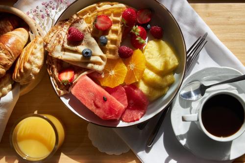 a plate of waffles with fruit and a cup of coffee at Monika Centrum Hotels in Rīga