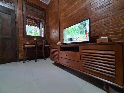 sala de estar con TV y pared de ladrillo en La Tavisa Hotel Borobudur en Magelang