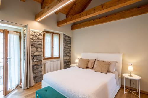 a bedroom with a white bed and a stone wall at Bed & Bike La Stalla in Masera