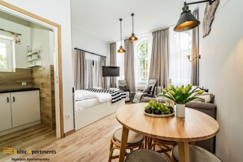 ein Wohnzimmer mit einem Tisch und ein Schlafzimmer in der Unterkunft Baltic Apartments - Willa Carmen in Świnoujście