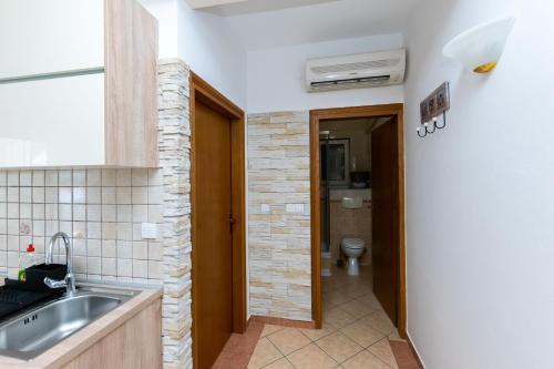 a kitchen with a sink and a toilet in a room at Apartments Miranda in Lopar