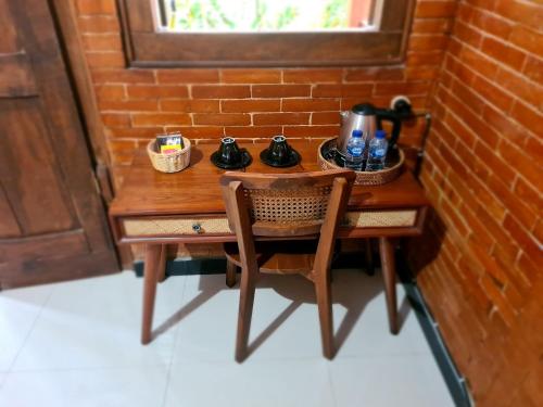 a wooden table with a tea kettle and a chair at La Tavisa Hotel Borobudur in Magelang