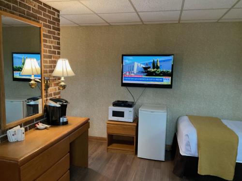 a hotel room with a bed and a tv on the wall at Motel & Hotel La Paysanne in Sherbrooke