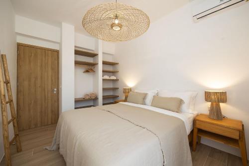 a bedroom with a white bed and a chandelier at The Nine Graces - Kastraki Villas with Private Swimming Pool in Kastraki Naxou
