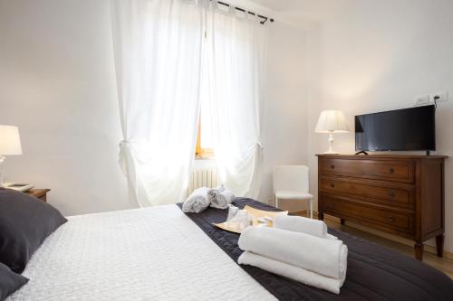 a bedroom with a bed with a dresser and a television at Hotel Porta Romana di Luce Hotels in Siena