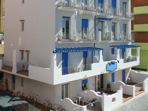 duży biały budynek z niebieskimi balkonami i stołami w obiekcie Vibrant Apartment in Rimini with Balcony w Rimini