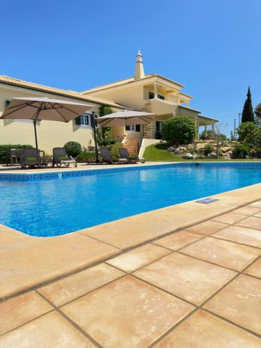 a swimming pool in front of a house at Villa Tranberg Suites in Ferreiras