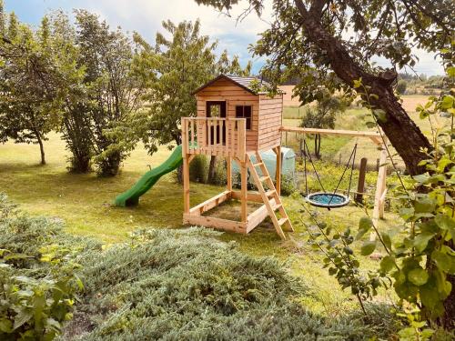 un parque infantil de madera con un tobogán y un árbol en Folwark Minikowo - Agroturystyka w Borach Tucholskich - 5 pokoi - 1 do 25os, en Bysław