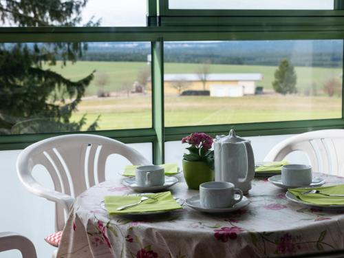 einen Tisch mit Tassen und Untertassen auf einem Tisch mit Fenster in der Unterkunft Apartment G 25 by Interhome in Dittishausen