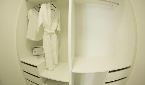 a white closet with white clothes hanging on a rack at Biarritz Hplus Long Stay in Brasília