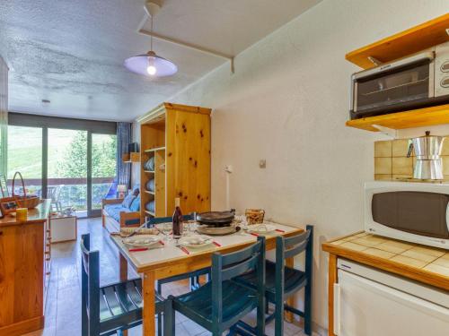 a kitchen with a table with chairs and a microwave at Studio Cosmos-1 by Interhome in Le Corbier