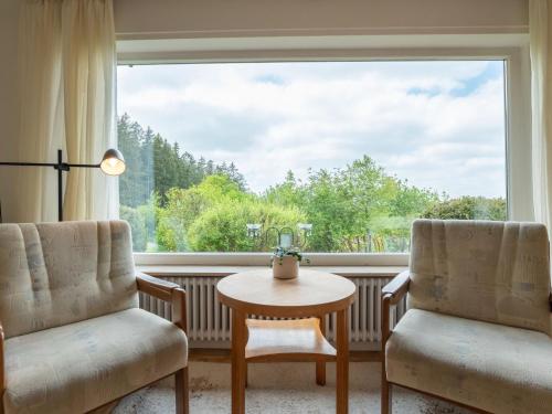 une chambre avec deux chaises, une table et une grande fenêtre dans l'établissement Holiday Home Sonnenbühl by Interhome, à Dittishausen