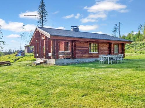 uma cabana de madeira com uma mesa e cadeiras à sua frente em Holiday Home Honkakoti by Interhome em Kurkimaki