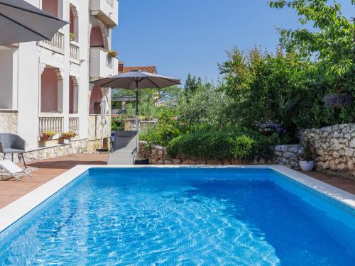 a swimming pool in front of a house with an umbrella at Apartment Romantika - ROJ108 by Interhome in Rovinj