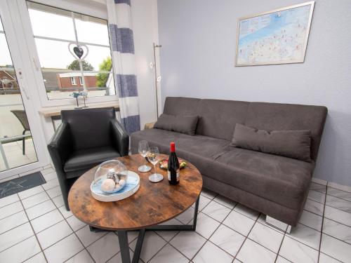 uma sala de estar com um sofá e uma mesa com copos de vinho em Apartment Krabbe by Interhome em Norddeich