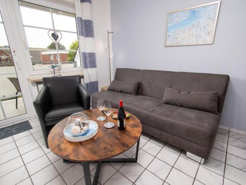 ein Wohnzimmer mit einem Sofa und einem Tisch mit Weingläsern in der Unterkunft Apartment Krabbe by Interhome in Norddeich