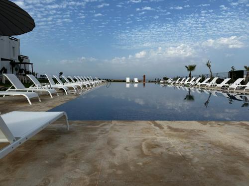 a row of chairs sitting next to a pool of water at PLAYA DEL PACHA Suites Hotel in Marina Smir