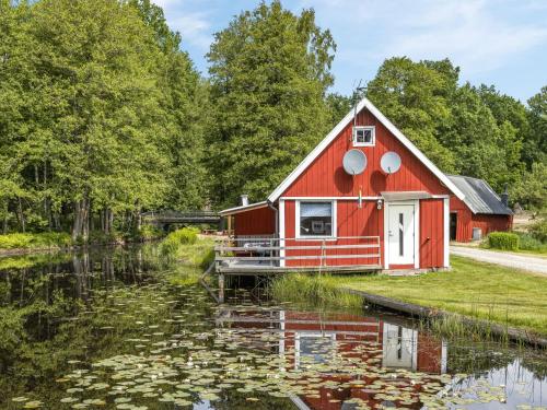 a red barn next to a pond with water lilies at Holiday Home Tingsmåla by Interhome in Tingsryd